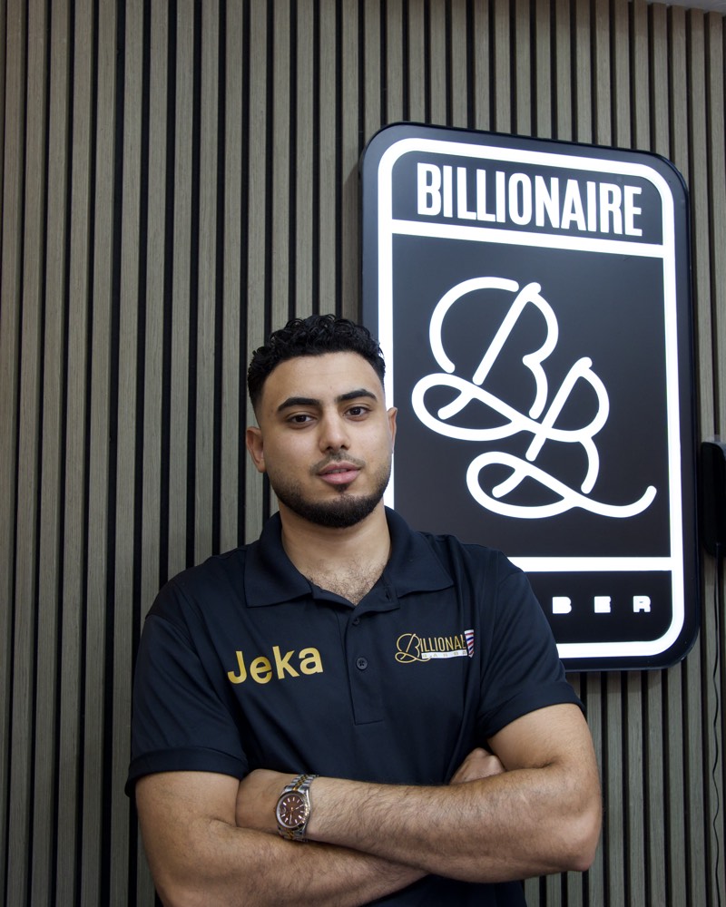 John, owner of Billionaire Barber, in front of the shop's illuminated BB sign